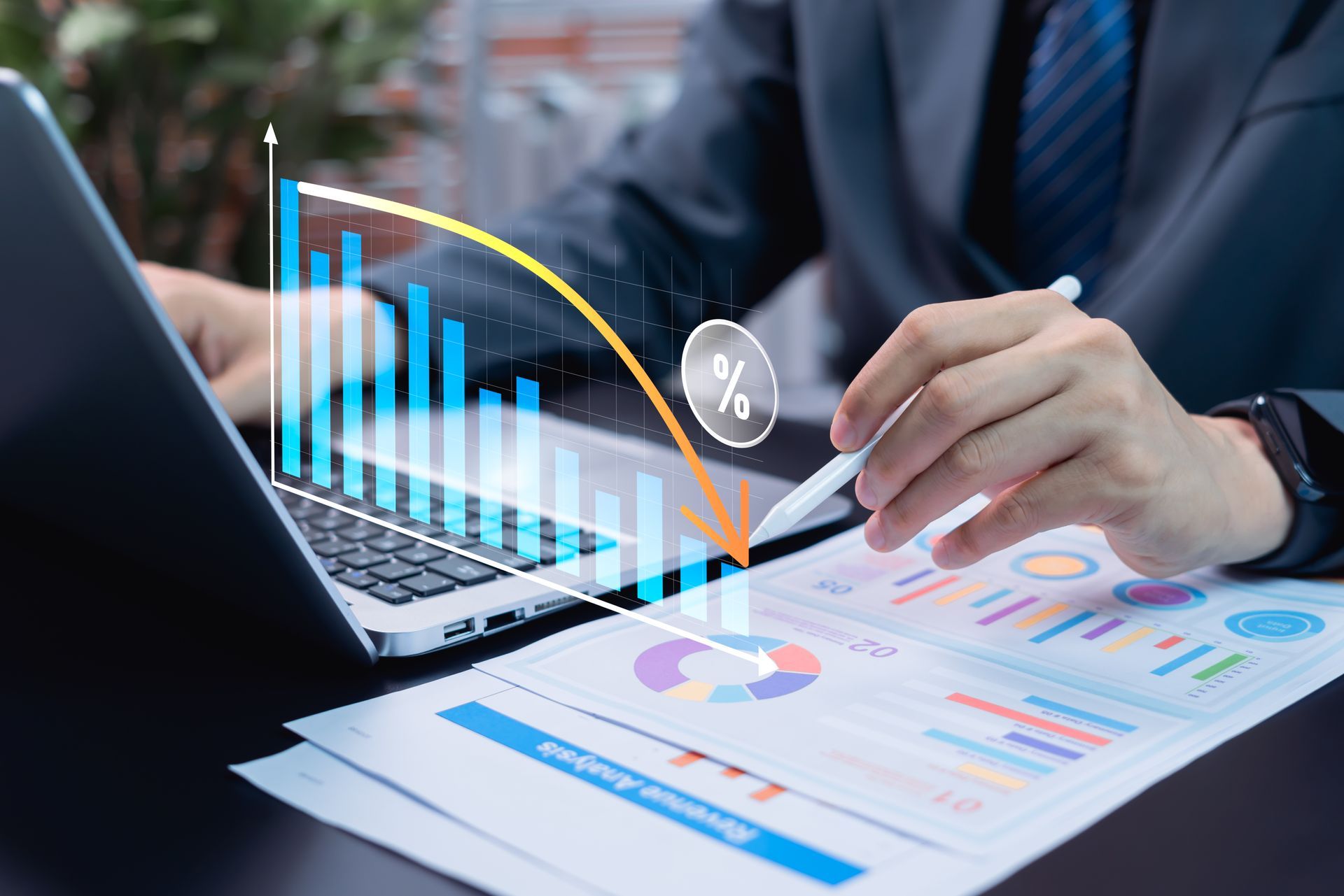 Une personne en costume analyse des graphiques financiers sur un ordinateur portable et sur papier, avec un graphique de tendance à la baisse superposé.