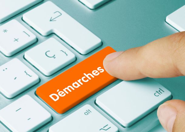 Le doigt appuie sur une touche du clavier portant la mention Démarches sur un ordinateur portable.