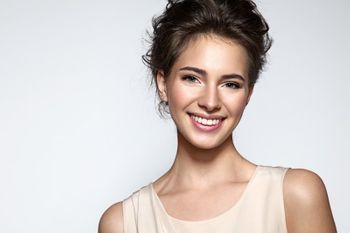 Frau umrahmt ihr Gesicht mit den Händen und lächelt