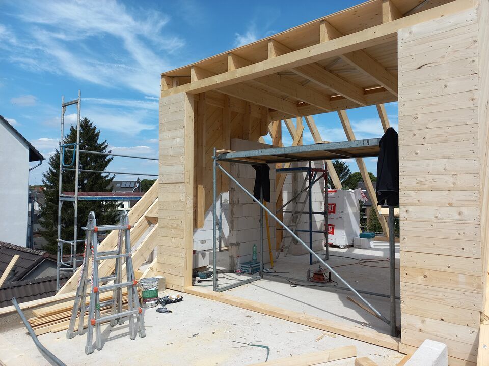Ein Haus wird mit Holzbalken und Gerüsten gebaut.