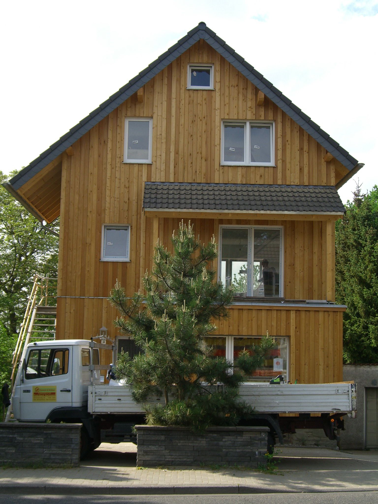 Ein weißer LKW steht vor einem Holzhaus
