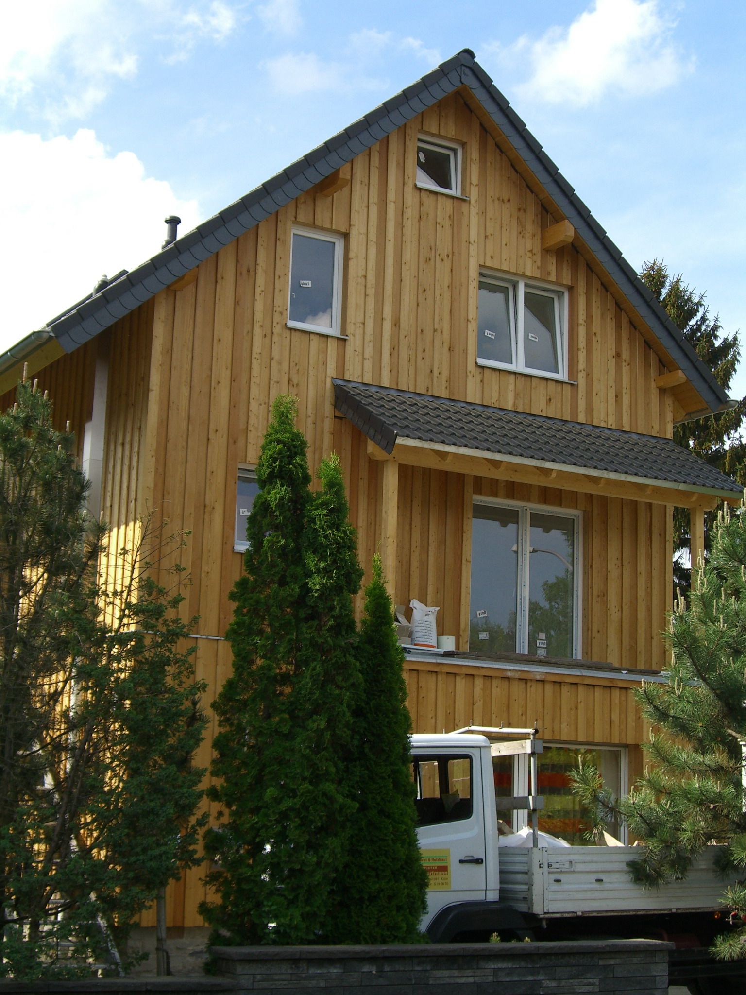 Ein weißer LKW steht vor einem Holzhaus
