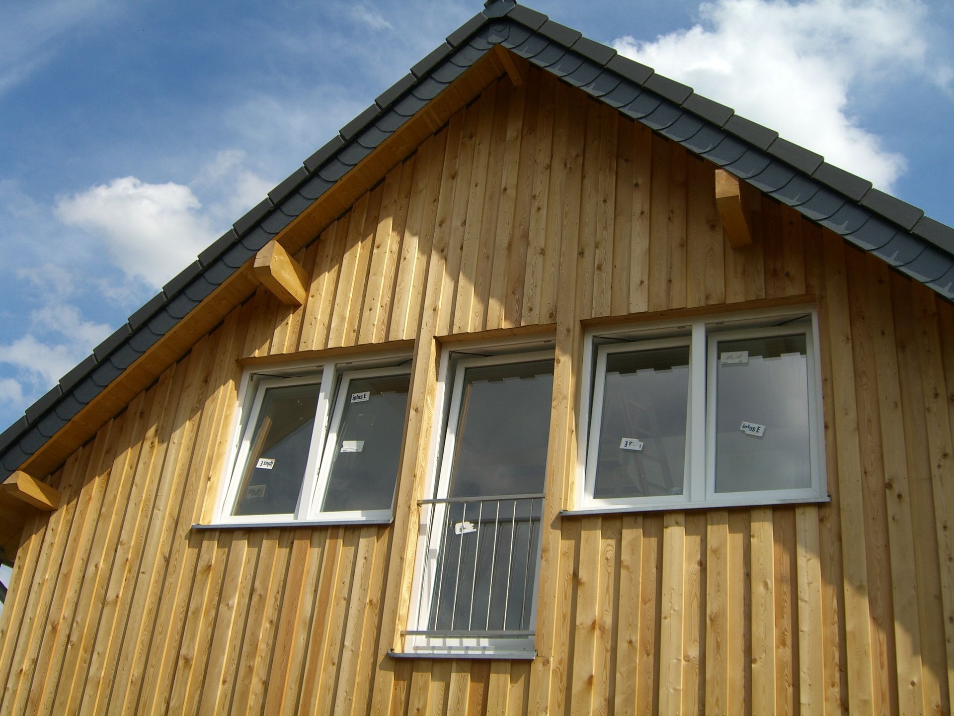 Ein Holzhaus mit drei Fenstern und einem Dach