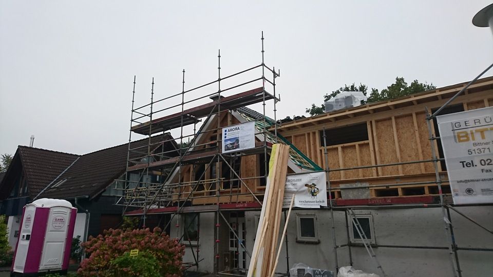 Es wird ein Haus mit Gerüsten und mobilen Toiletten gebaut.