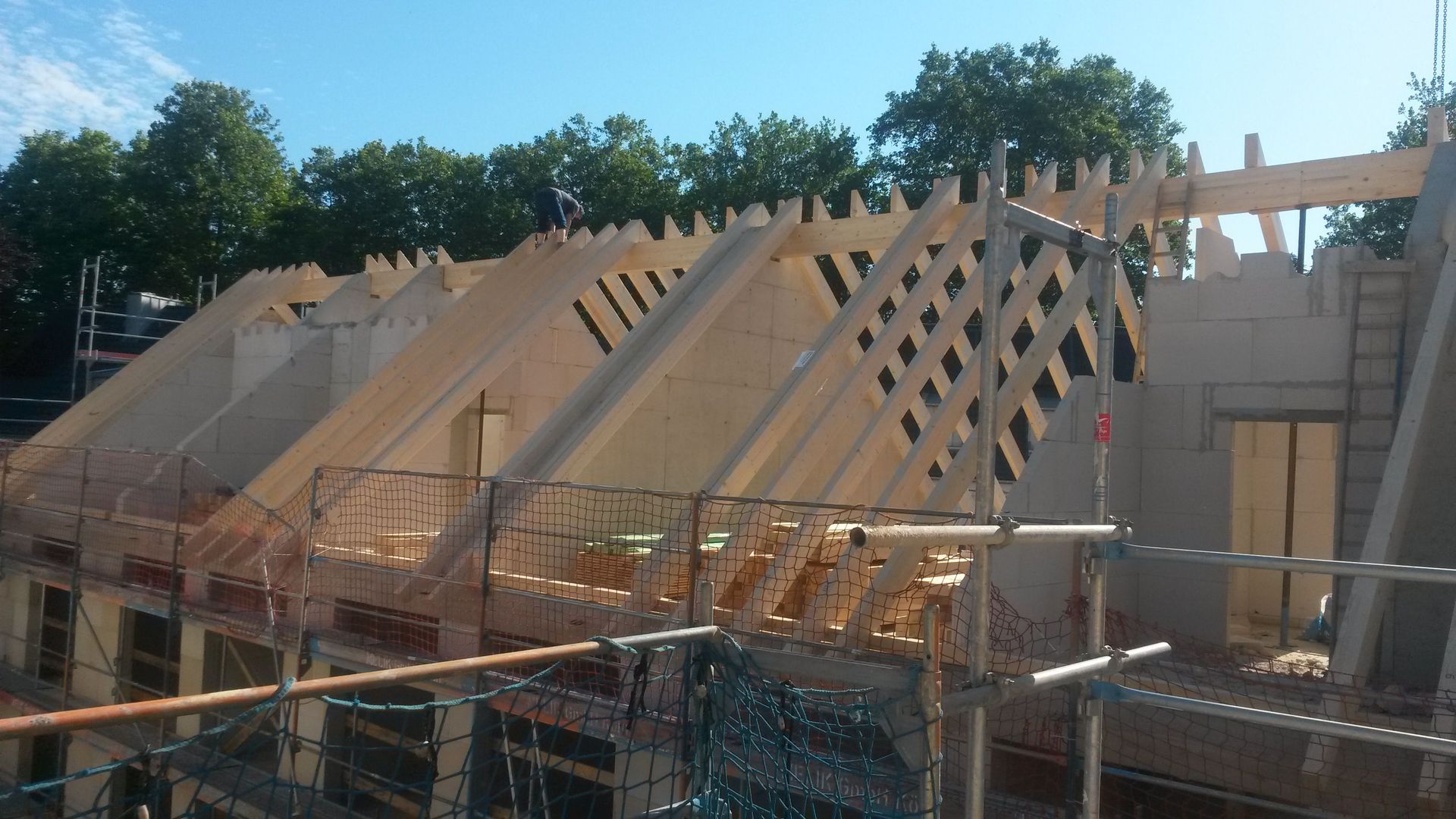 Auf einem im Bau befindlichen Gebäude wird eine Reihe Holzdächer errichtet.