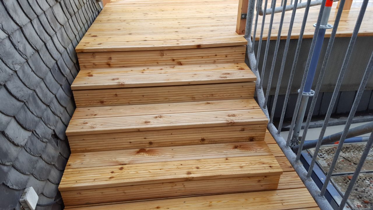 Eine Holztreppe führt hinauf zu einem Balkon.