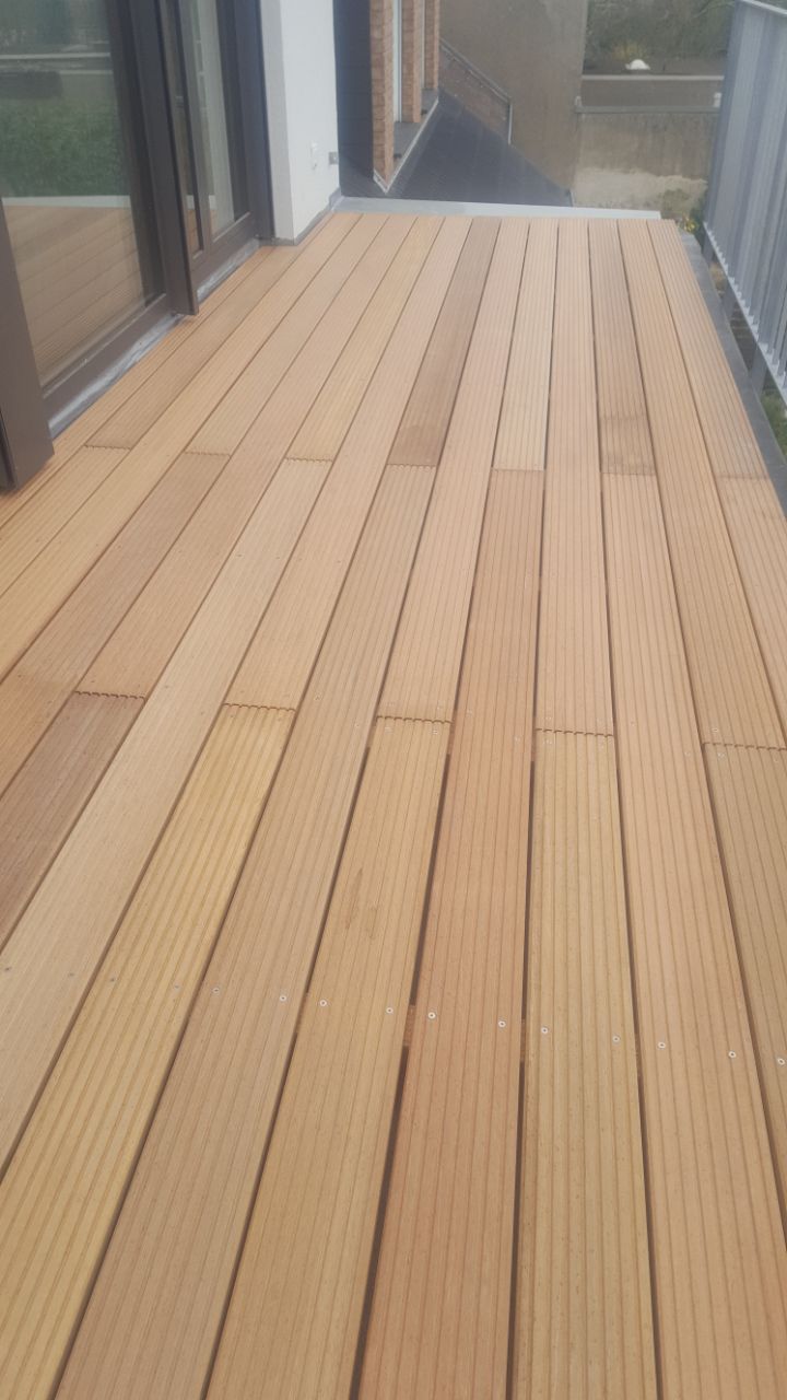 Ein Holzdeck mit einer Glasschiebetür im Hintergrund.