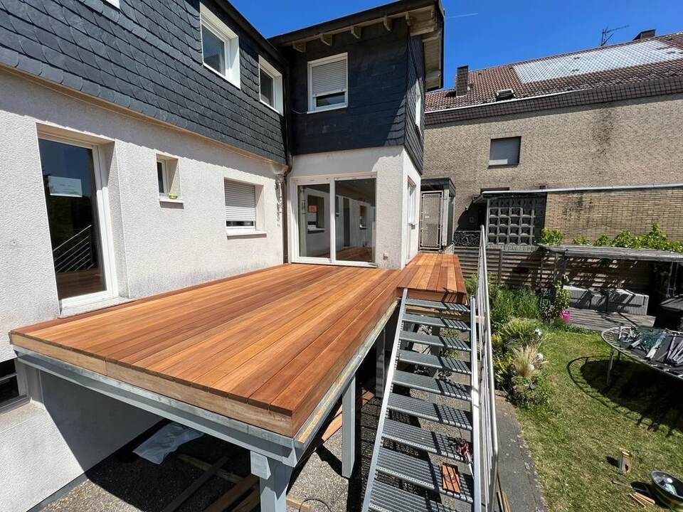 Ein Haus mit einer Holzterrasse und einer Treppe, die dorthin führt