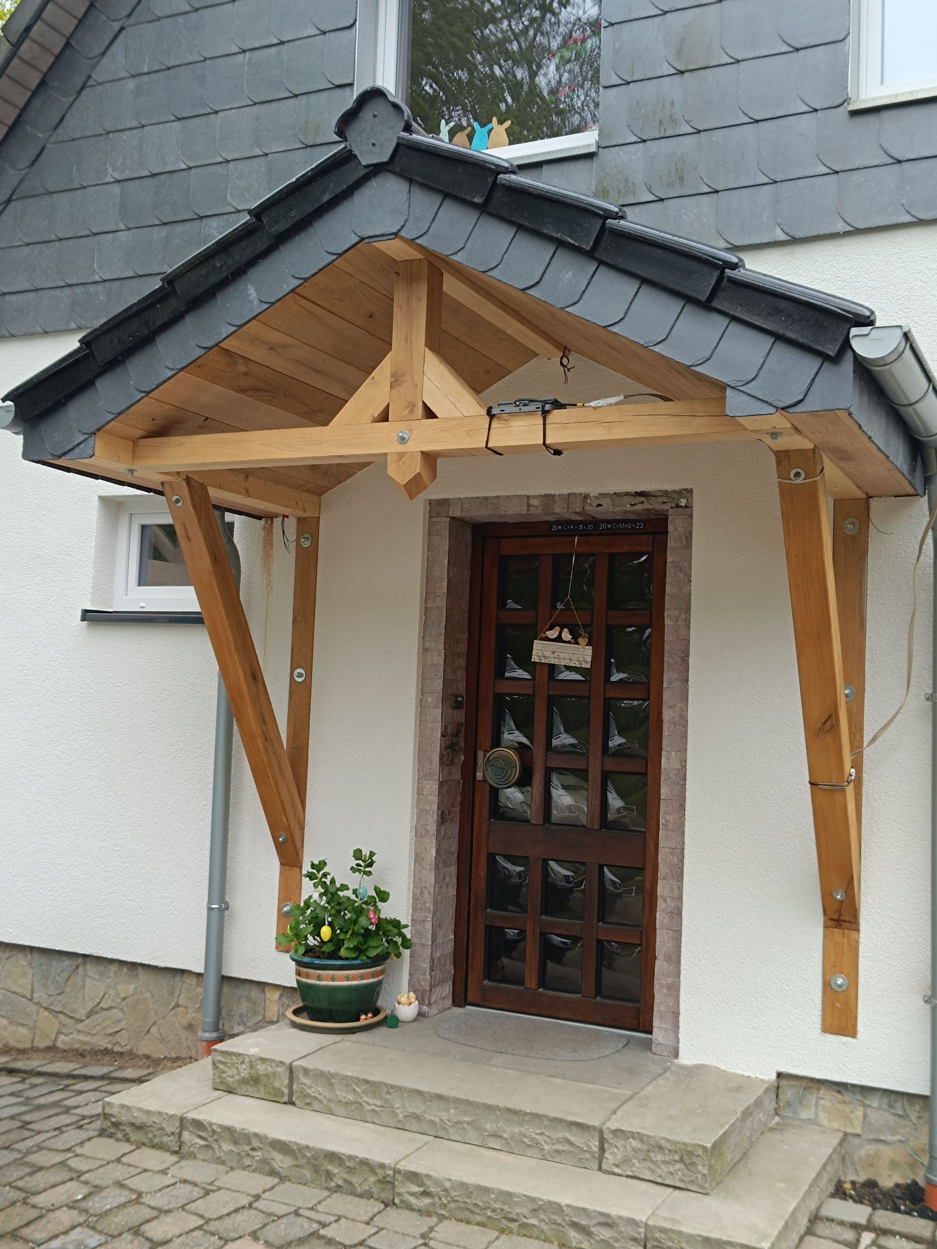 Ein weißes Haus mit einer Holzveranda über der Tür