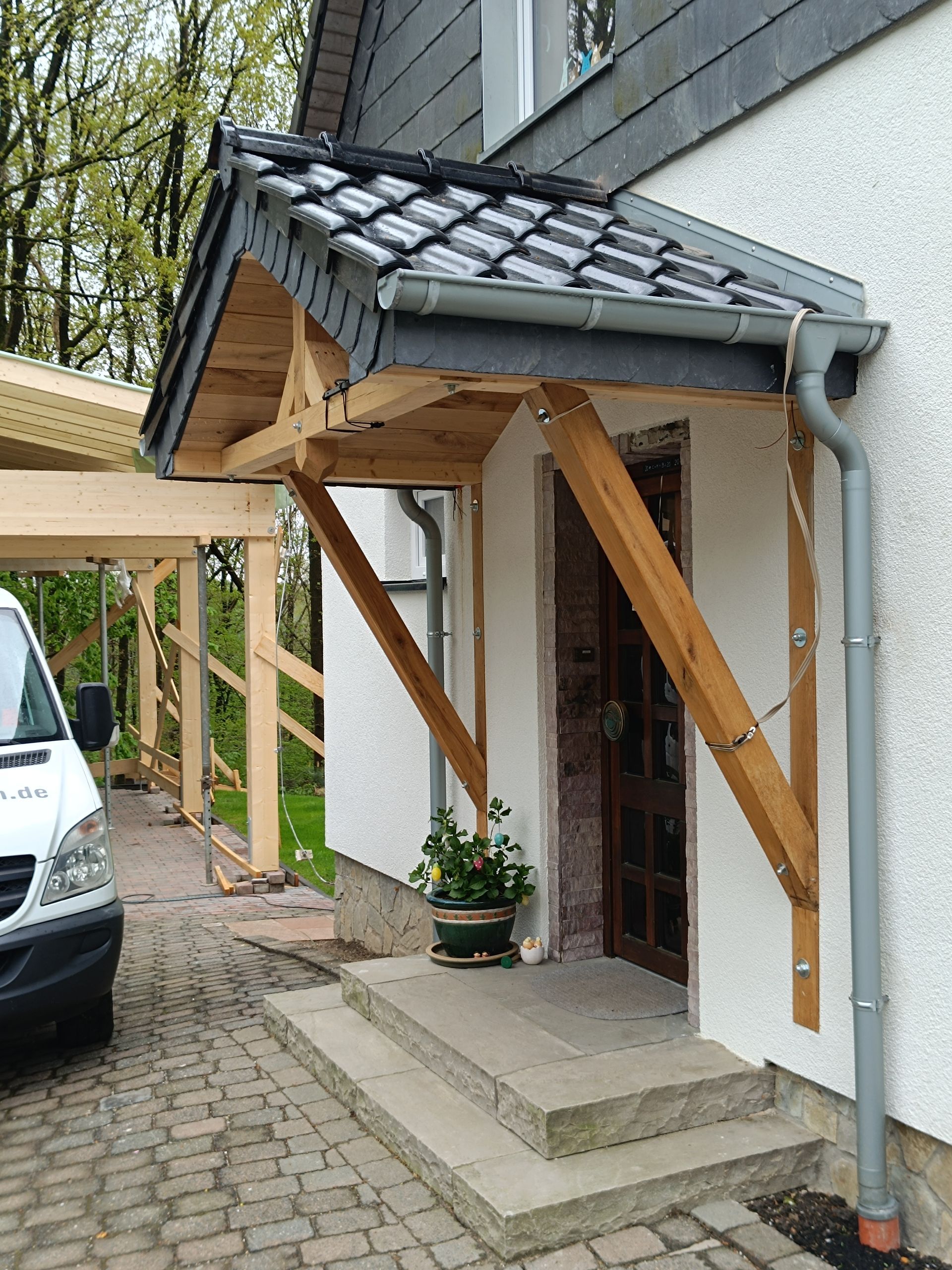 Ein weißer Lieferwagen steht vor einem Haus mit einer Holzveranda.