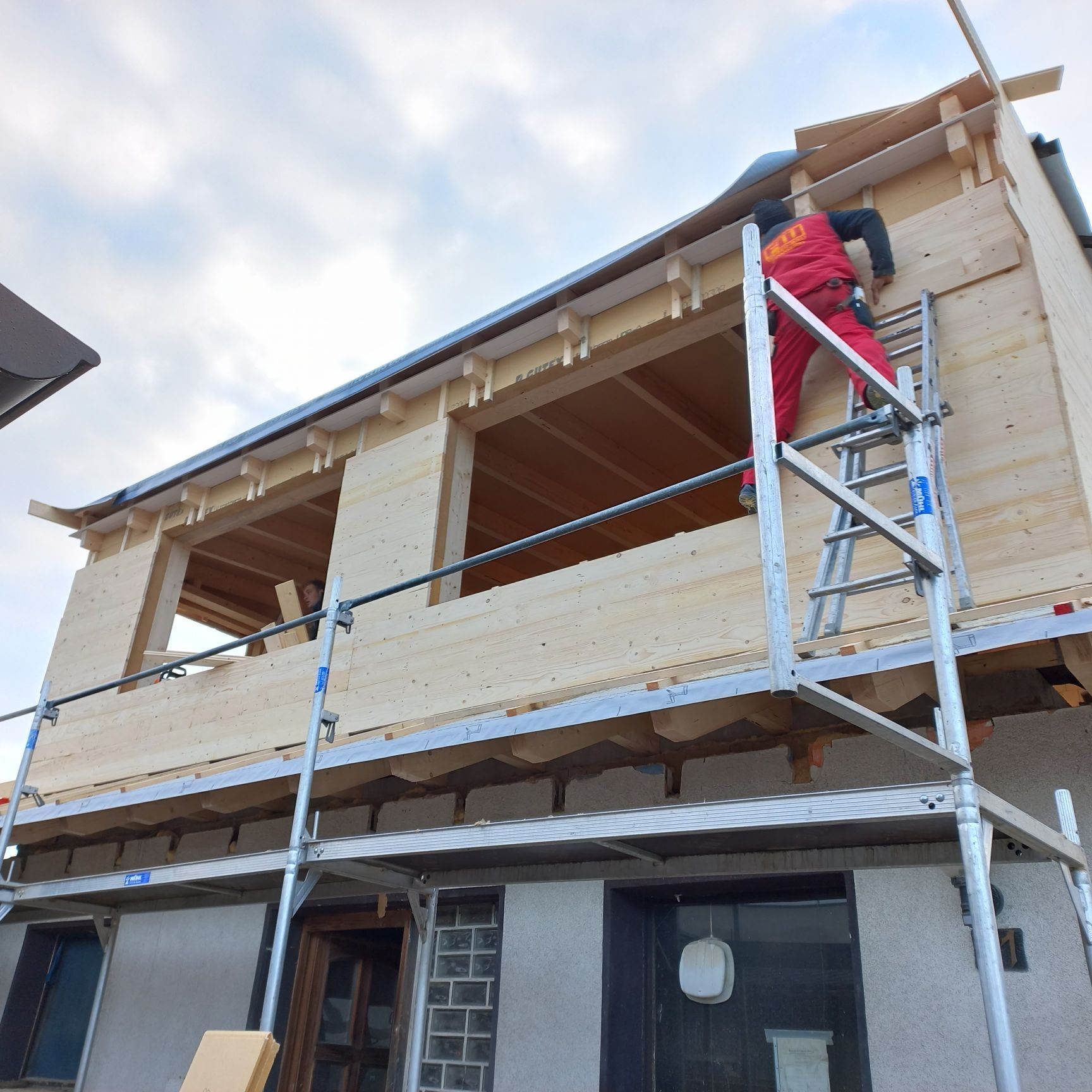 Ein Mann auf einer Leiter arbeitet an einem Holzgebäude