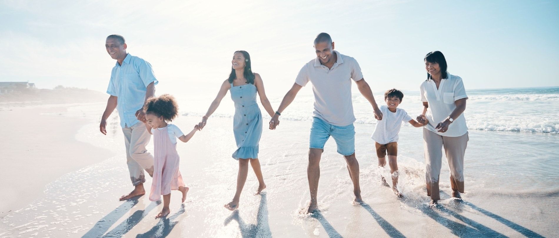 Una familia camina por la playa tomados de la mano.