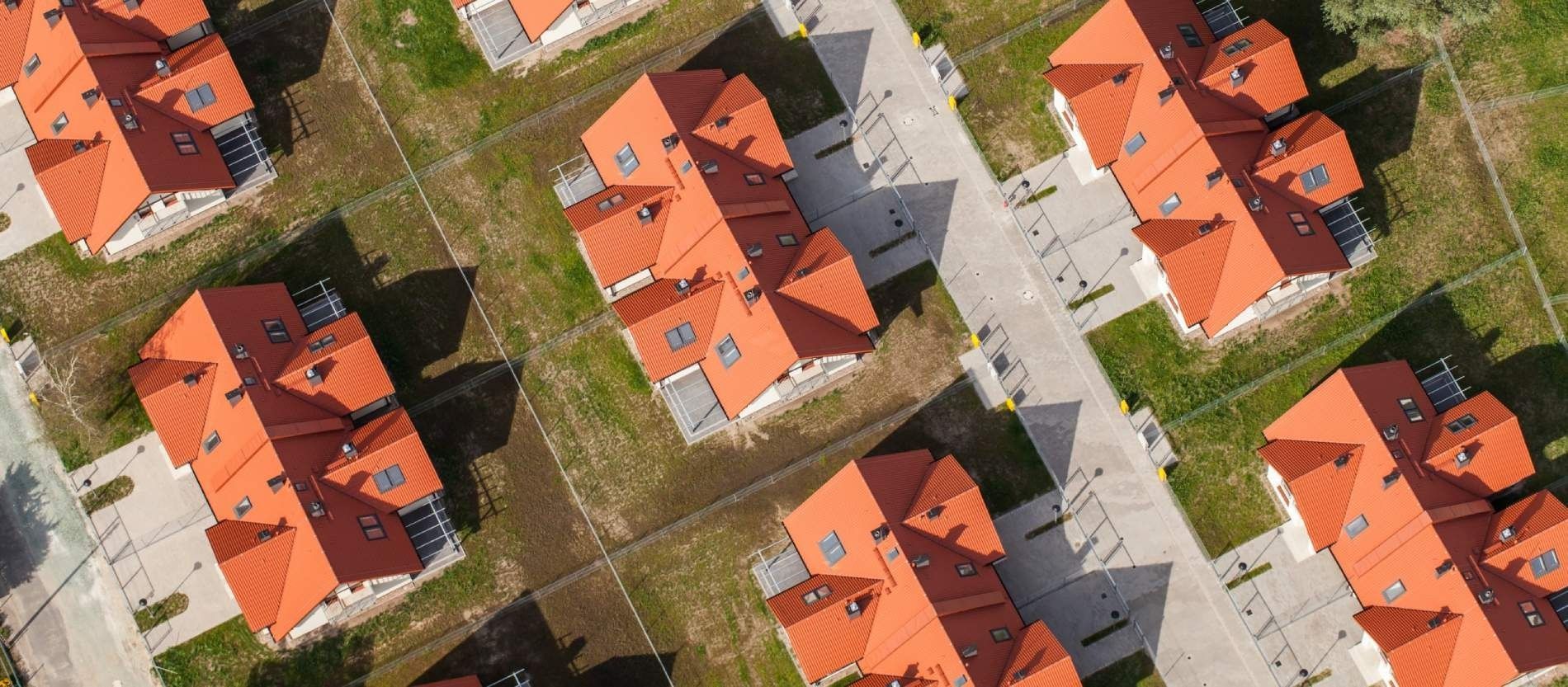 Una vista aérea de una hilera de casas con techos rojos en una zona residencial.