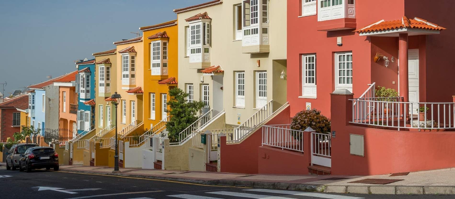 Una hilera de casas coloridas están alineadas en una calle.