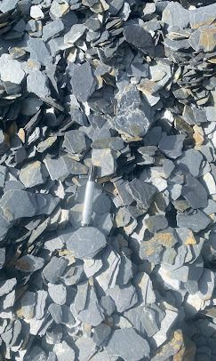 Un grand tas de pierres d'ardoise grises, plates et fragmentées.