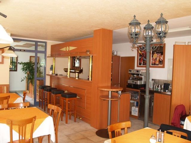 Gemütliches Restaurantinterieur mit Barhockern und Tischen aus Holz sowie Hängeleuchten.