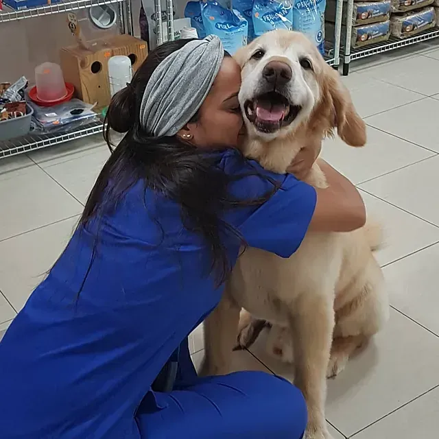 Una mujer con un uniforme azul abraza a un perro.