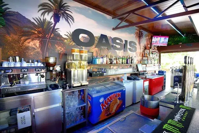 Un bar interior con temática de oasis, equipado con cafetera, dispensadores de granizados.