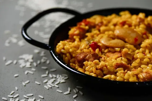 Un primer plano de una sartén de arroz con carne y frijoles sobre una mesa.