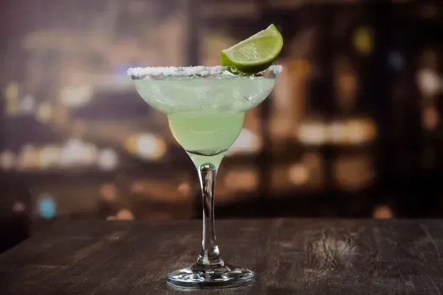 Una margarita con una rodaja de limón sobre una mesa de madera.