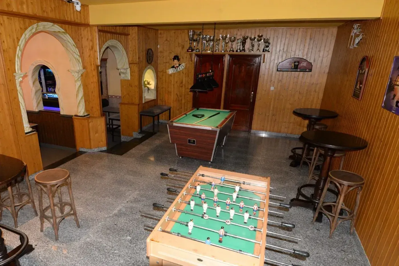Una sala de juegos con paneles de madera, que cuenta con una mesa de futbolín, una mesa de billar.