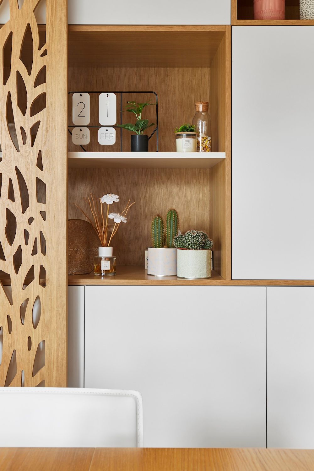 Étagères en bois avec petites plantes et objets décoratifs au-dessus de placards blancs dans une pièce moderne