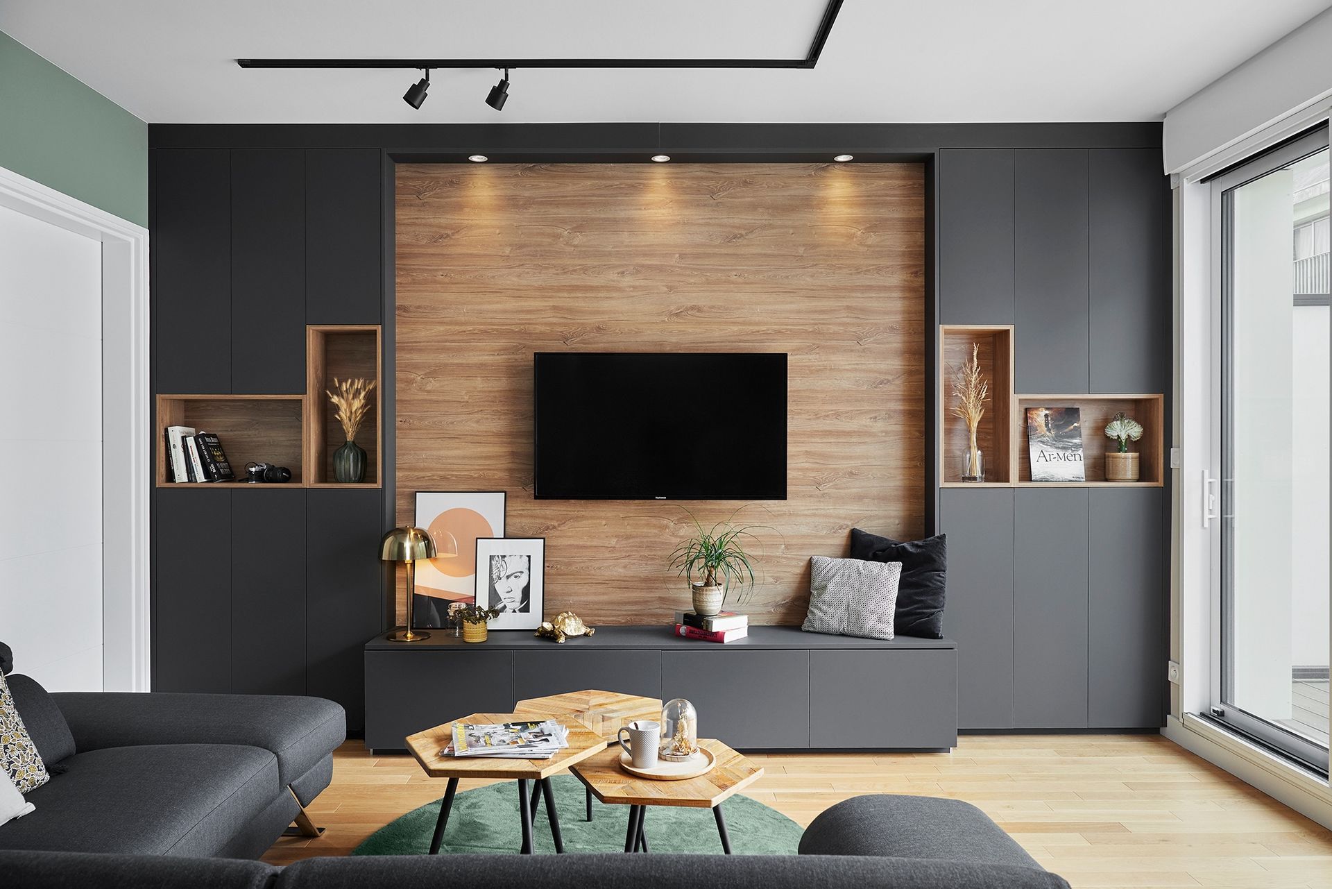 Salon moderne avec meubles encastrés foncés, mur d'accent en bois, télévision murale et grandes fenêtres