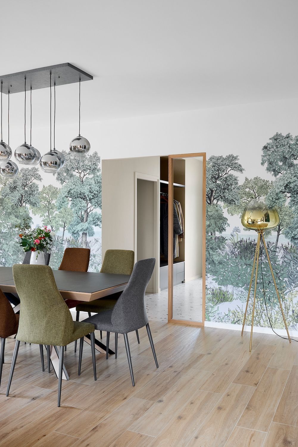 Salle à manger lumineuse avec table en bois, chaises grises et porte vitrée donnant sur le jardin.
