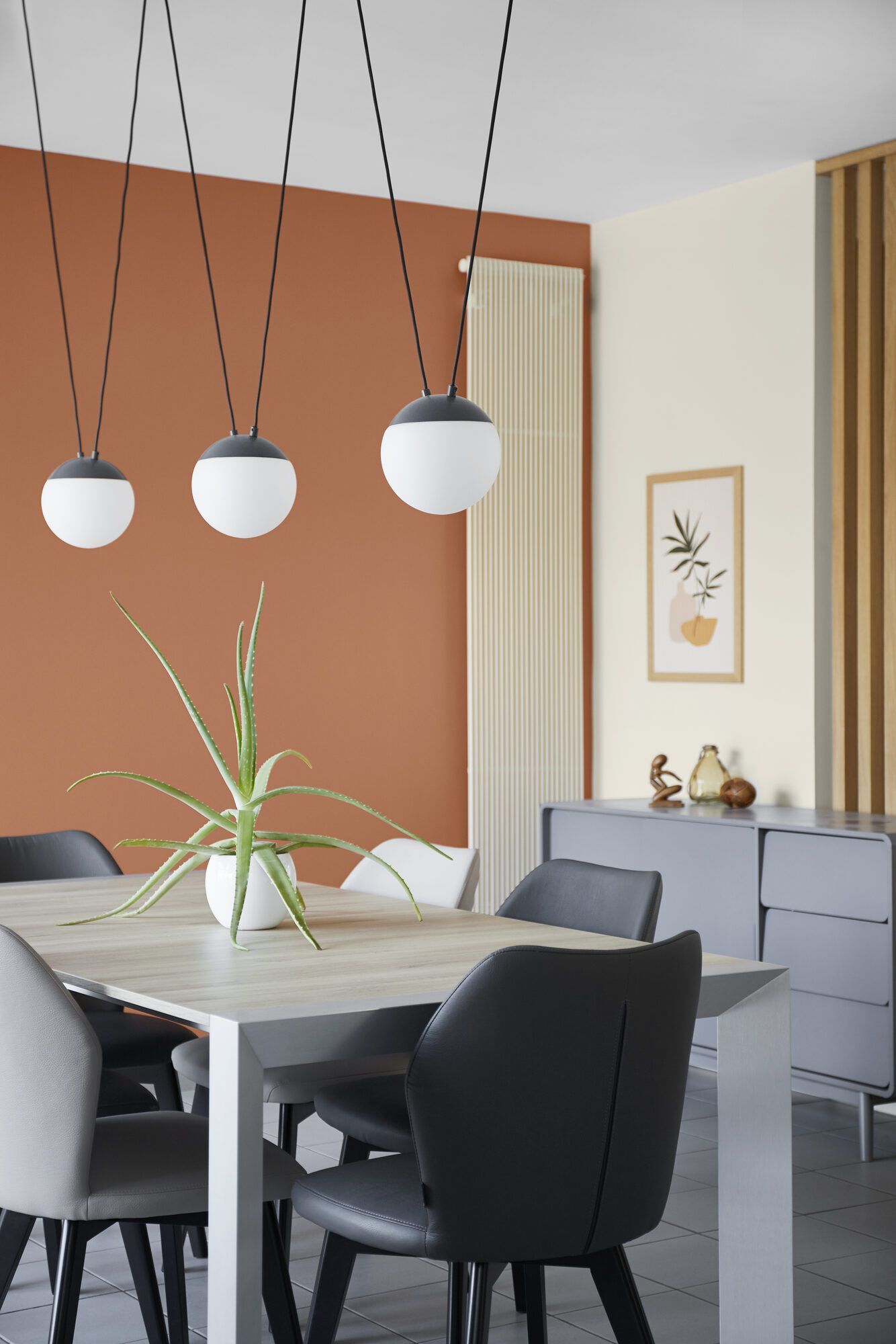Coin repas avec mur terracotta, suspensions boules et table bois, maison rénovée par Mathilde Design près de Nantes