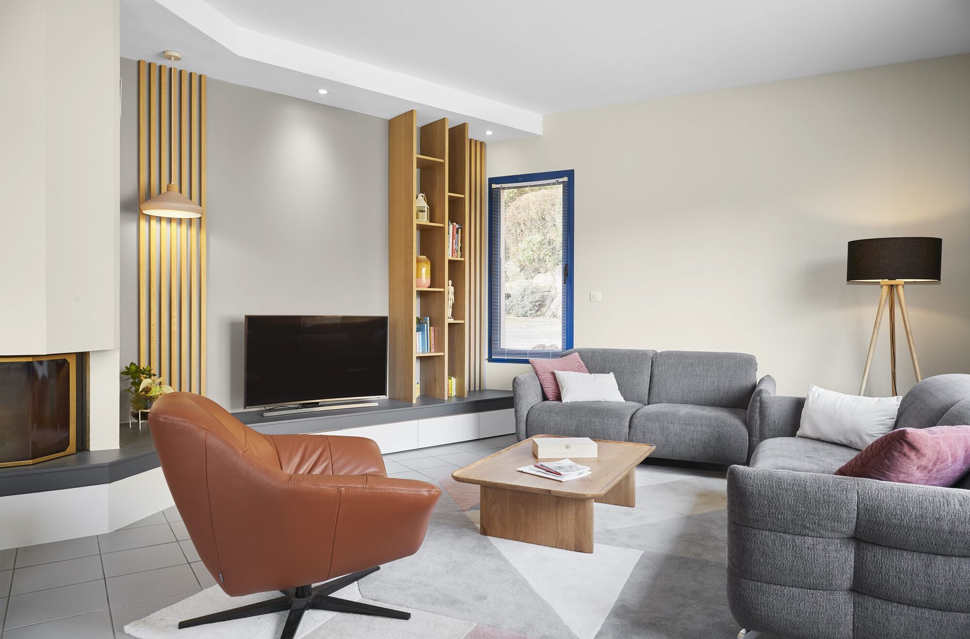 Rénovation de maison à Nantes : pièce de vie réaménagée par Mathilde Design, fauteuil cognac, canapés gris et bibliothèque sur mesure