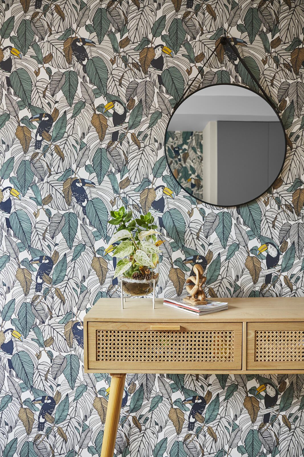 Console en rotin, miroir rond et papier peint toucans dans une entrée réaménagée par Mathilde Design, architecte d'intérieur Nantes
