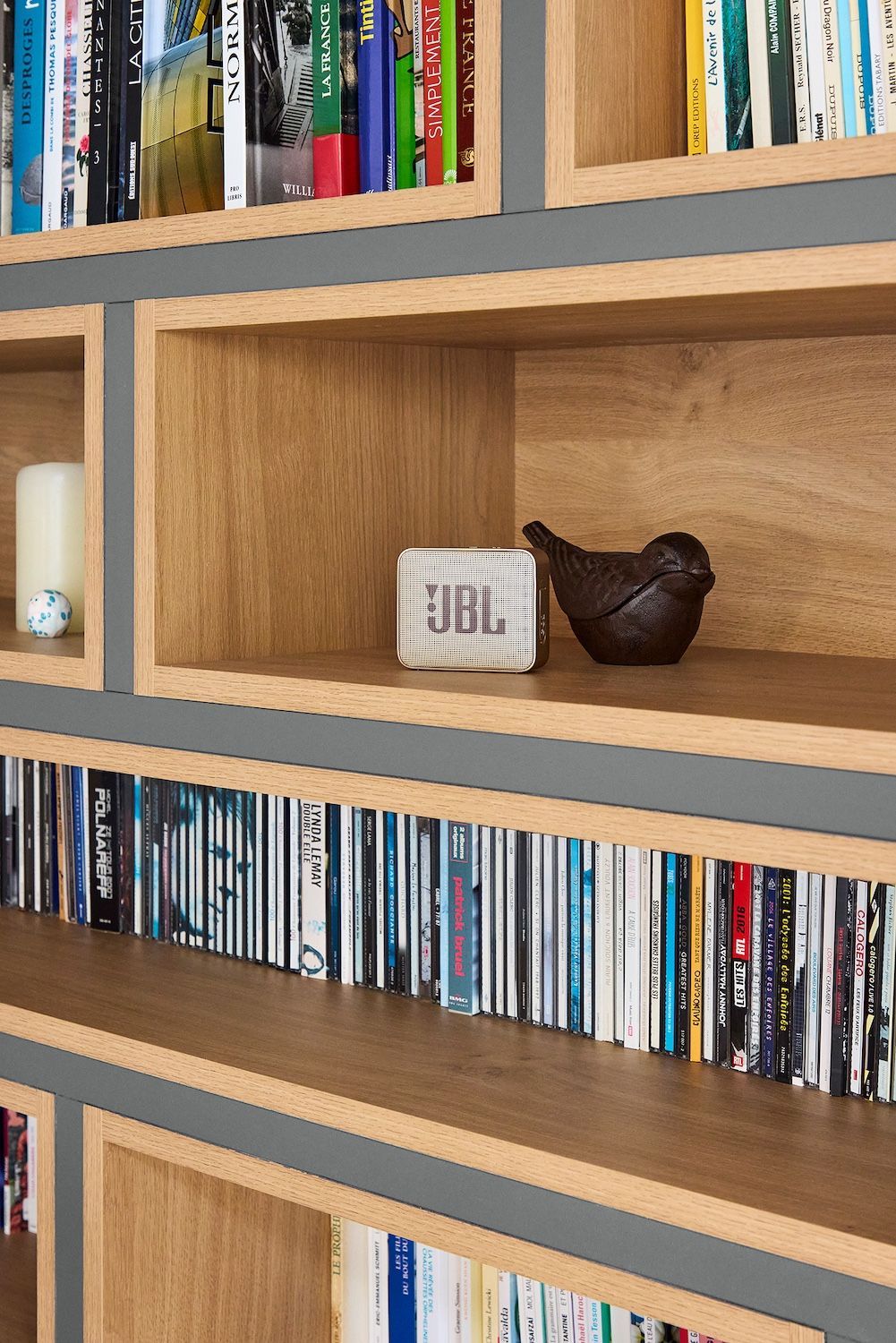 Étagère en bois avec des livres, une enceinte JBL et un bol décoratif foncé sur les étagères