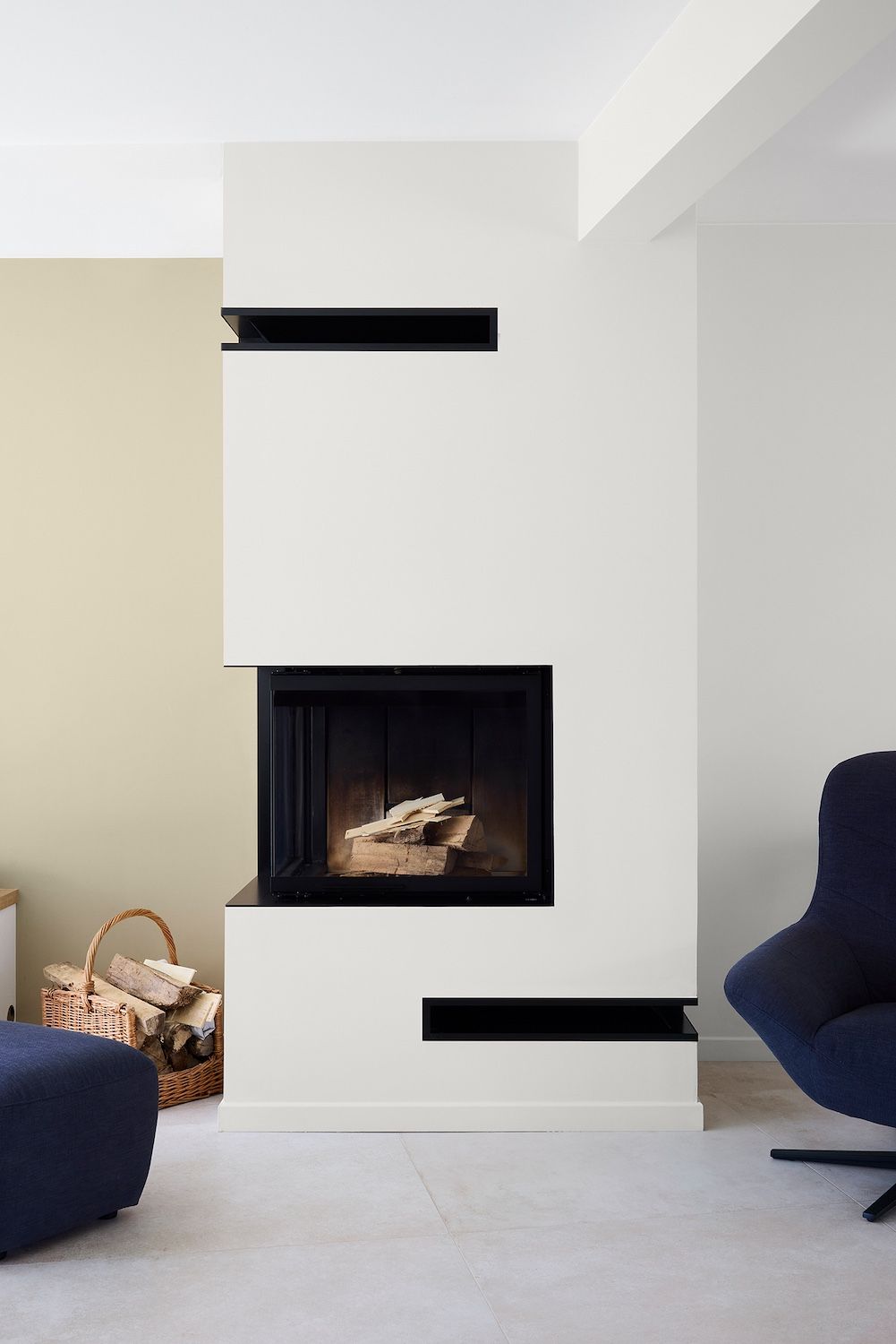 Salon moderne avec cheminée blanche, touches de noir et chaises bleu marine