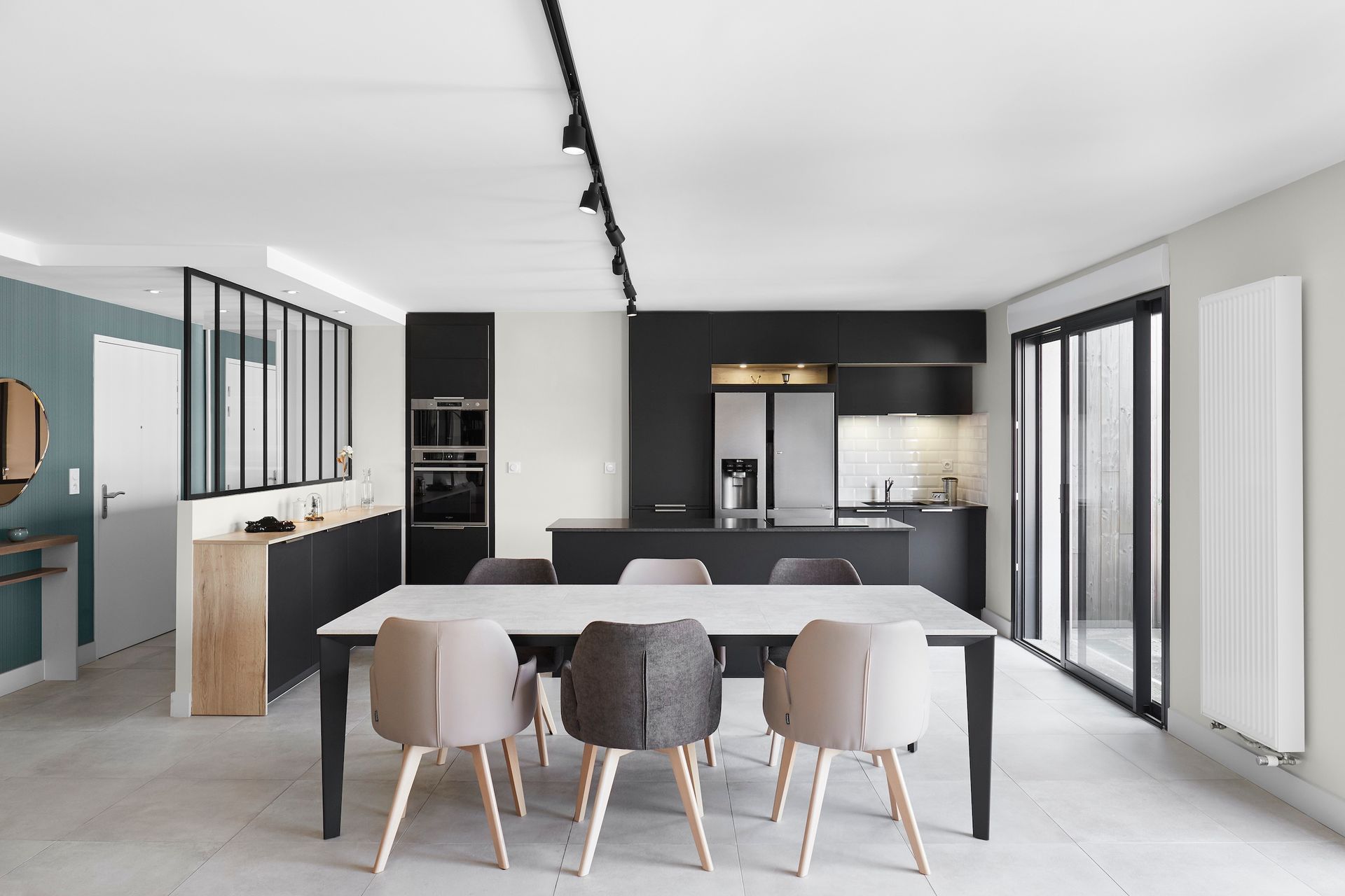 Cuisine et salle à manger modernes à aire ouverte avec murs blancs, armoires foncées, chaises grises et une longue table à manger