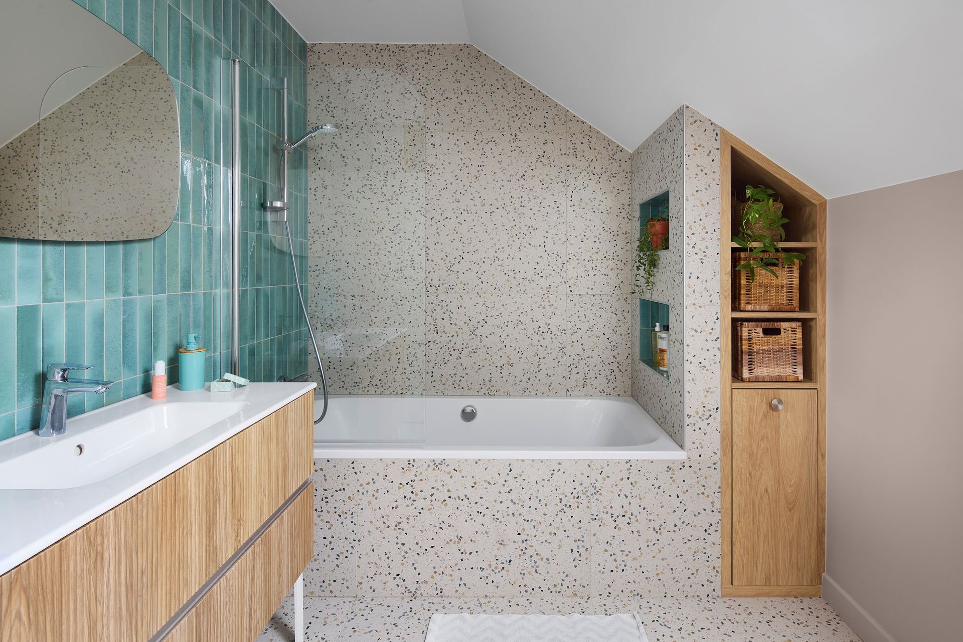 Salle de bains moderne avec carrelage turquoise, meuble-lavabo en bois, baignoire et étagères ouvertes.