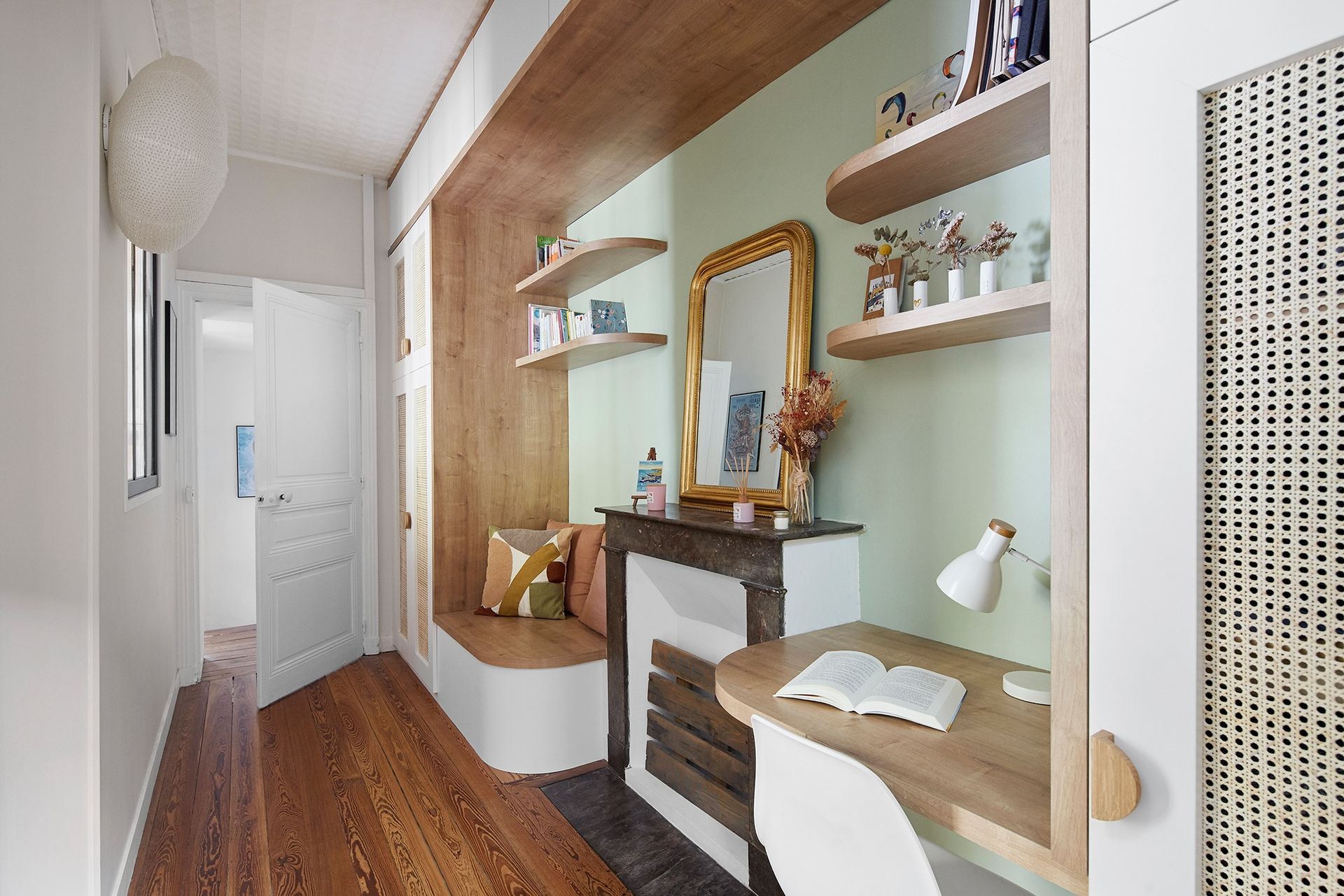 Couloir étroit avec parquet, murs vert menthe, cheminée, miroir, étagères, bureau et chaise blanche
