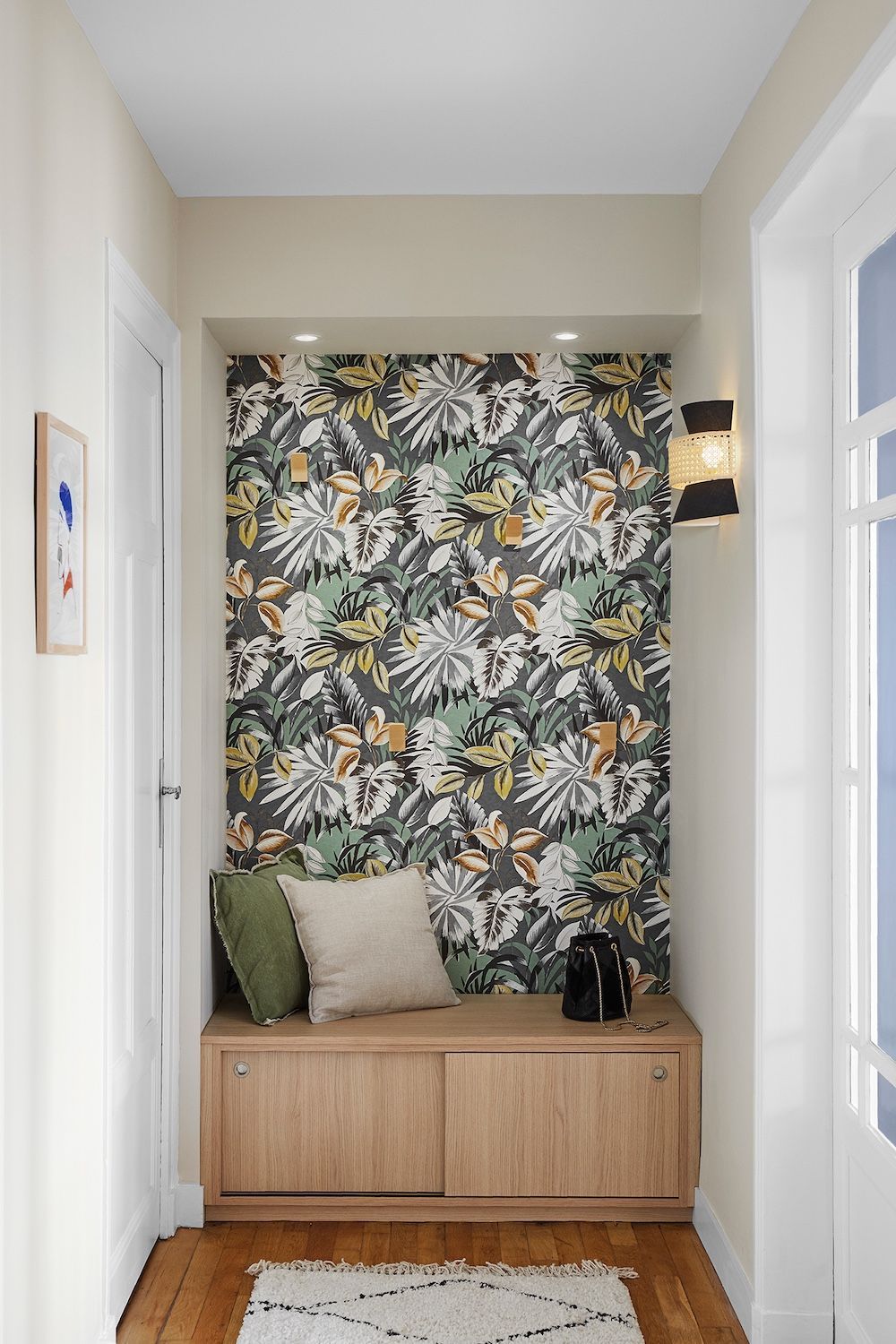 Couloir étroit avec papier peint à motifs floraux, banquette en bois intégrée, coussins et appliques murales.