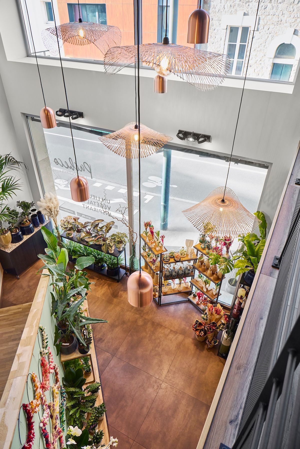 Cour intérieure moderne avec luminaires suspendus, plantes et un escalier entourant un espace central ouvert
