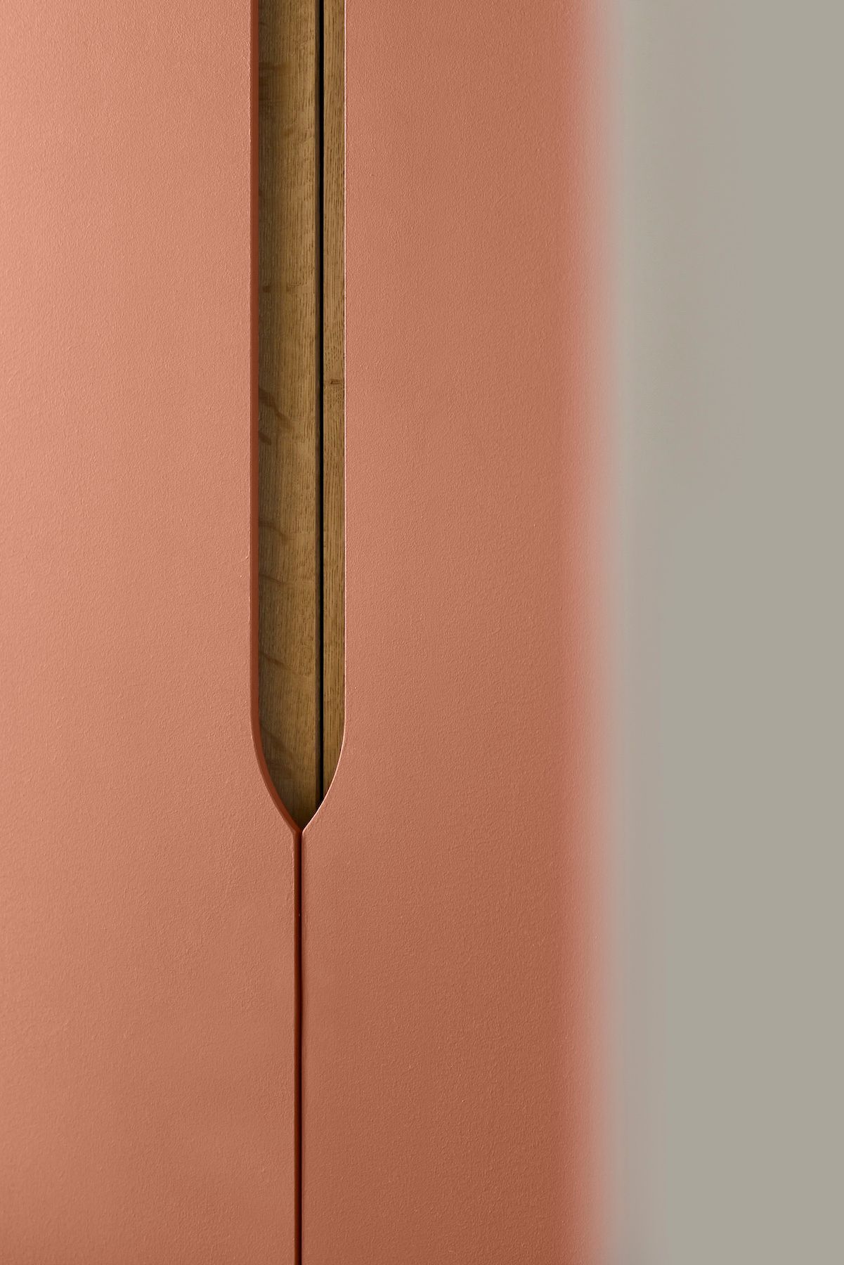 Gros plan sur une aiguille à coudre dorée enfilée dans un tissu rose, avec une couture centrée verticalement.