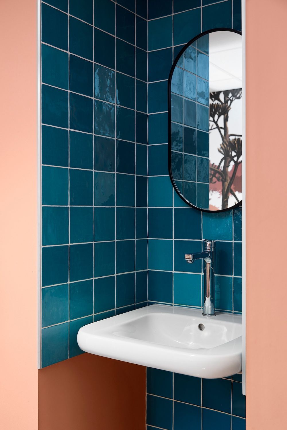 Porte vert foncé ornée d'une ligne et d'un cercle orange dans un couloir moderne, encadrée par des étagères en bois.