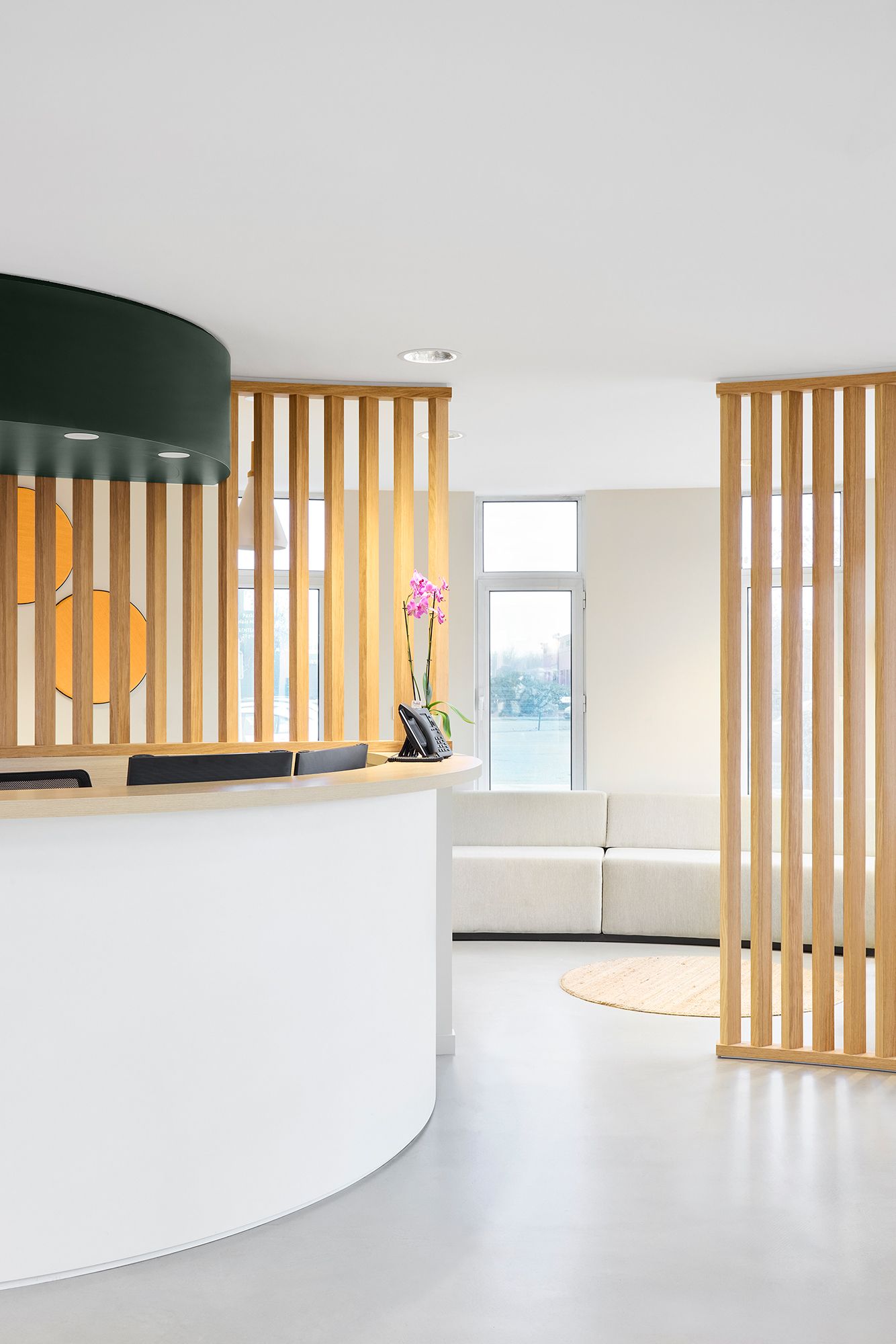 Coin bureau moderne avec bibliothèque en bois, mur végétal, banquette et grand arbre d'intérieur.