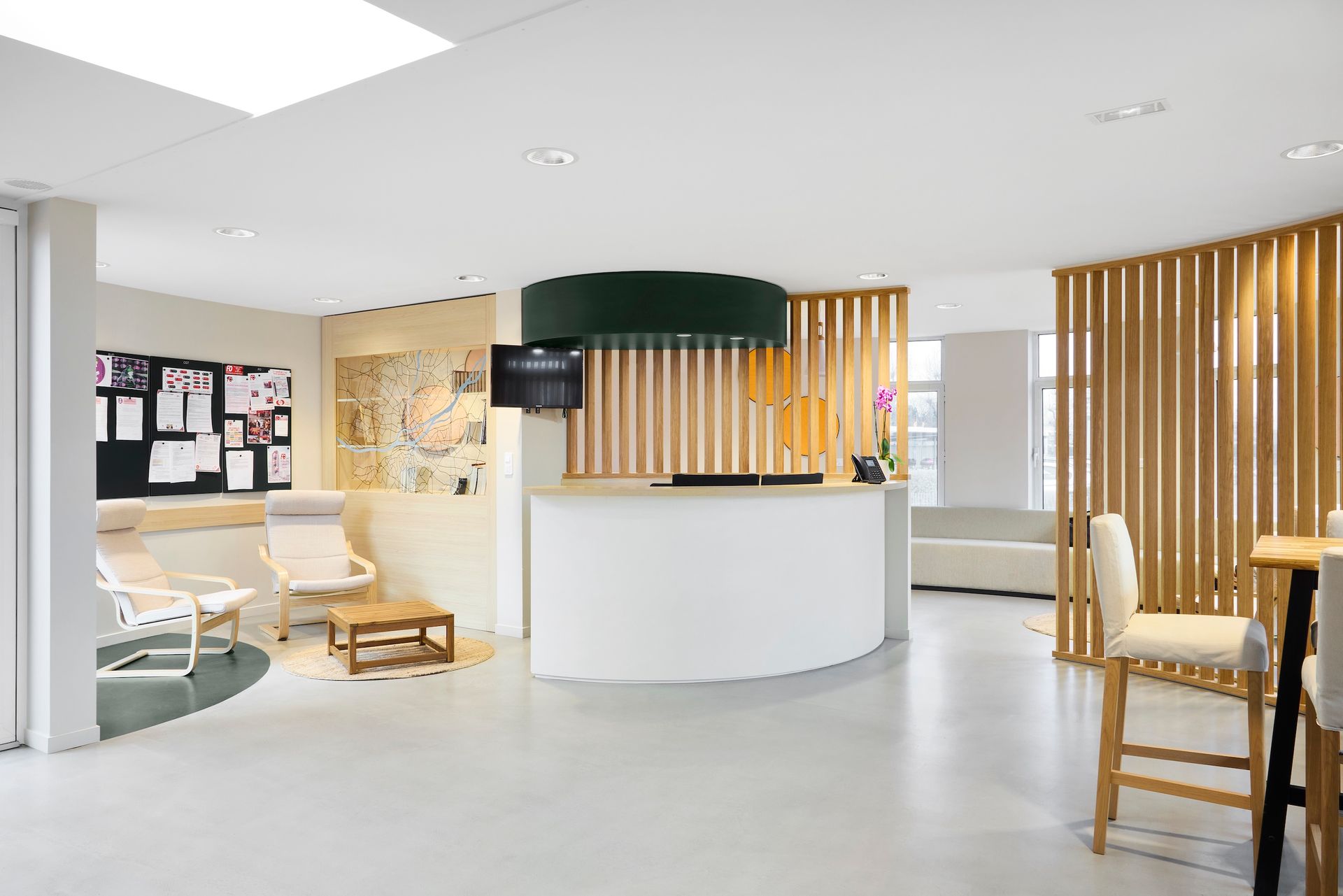 Espace d'accueil moderne avec bureau blanc incurvé, murs à lattes de bois, chaises beiges et sièges confortables.