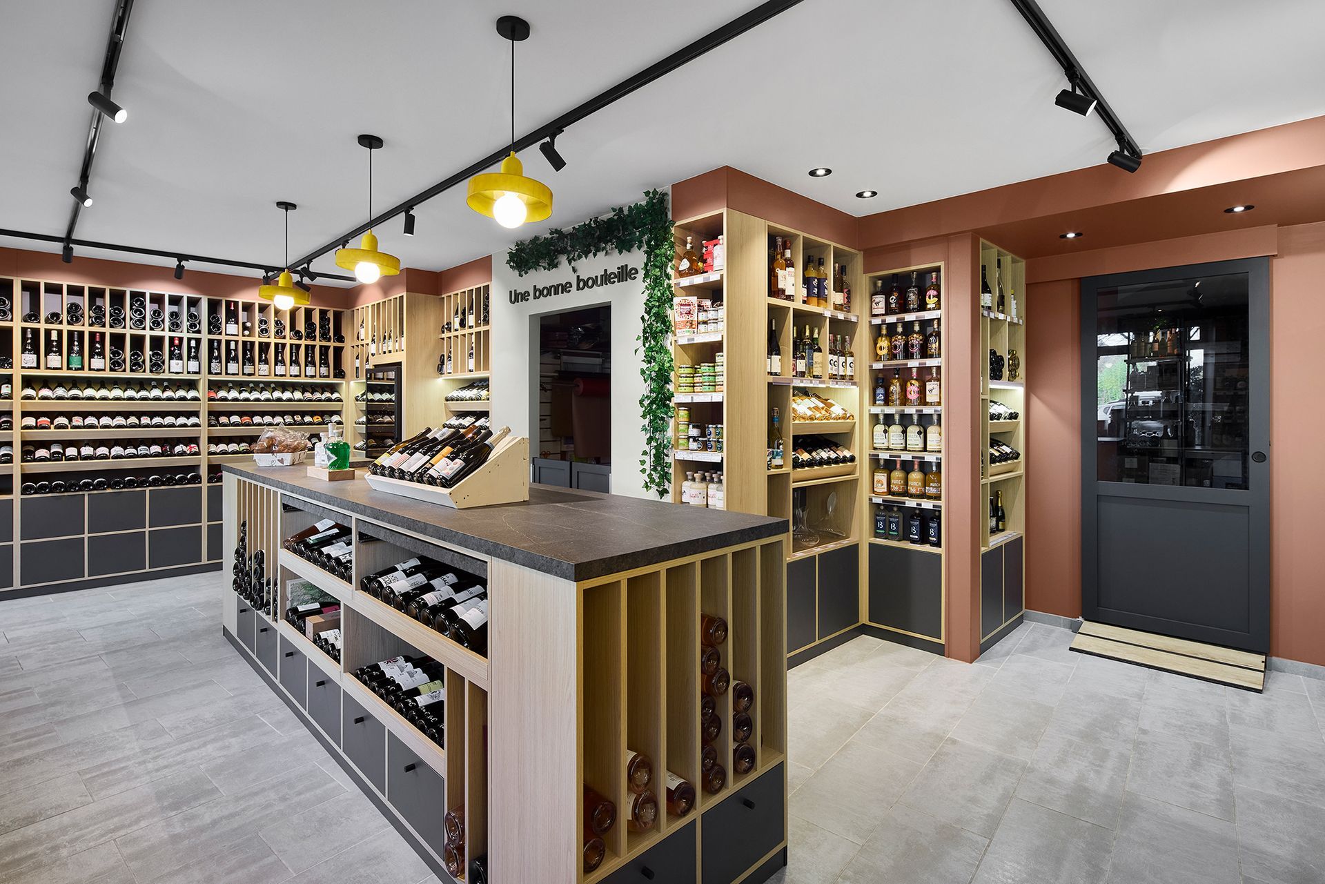 Intérieur moderne d'une cave à vin avec étagères, comptoirs d'exposition et luminaires suspendus.