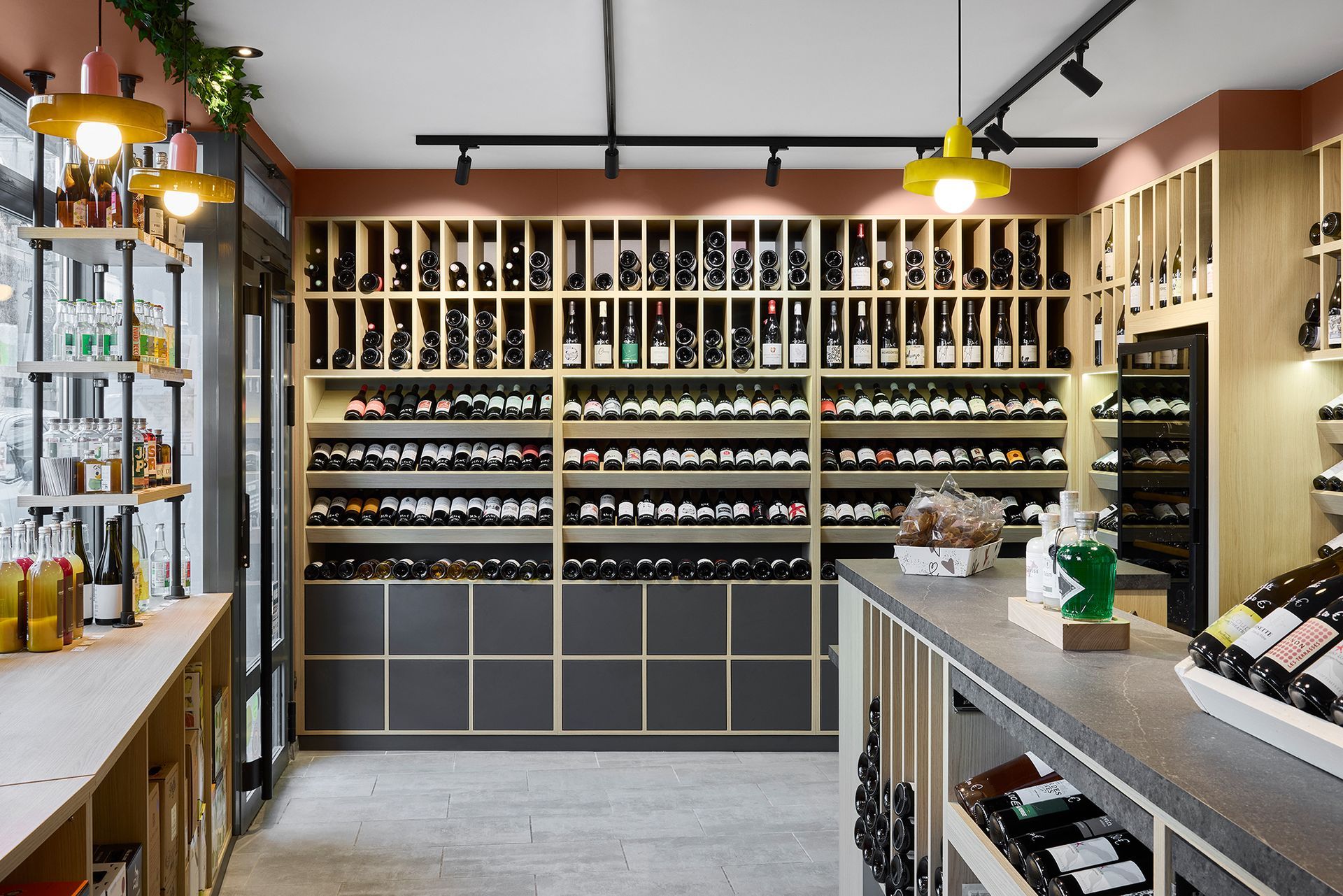 Intérieur d'une cave à vin avec étagères de bouteilles, comptoirs en bois et éclairage suspendu chaleureux