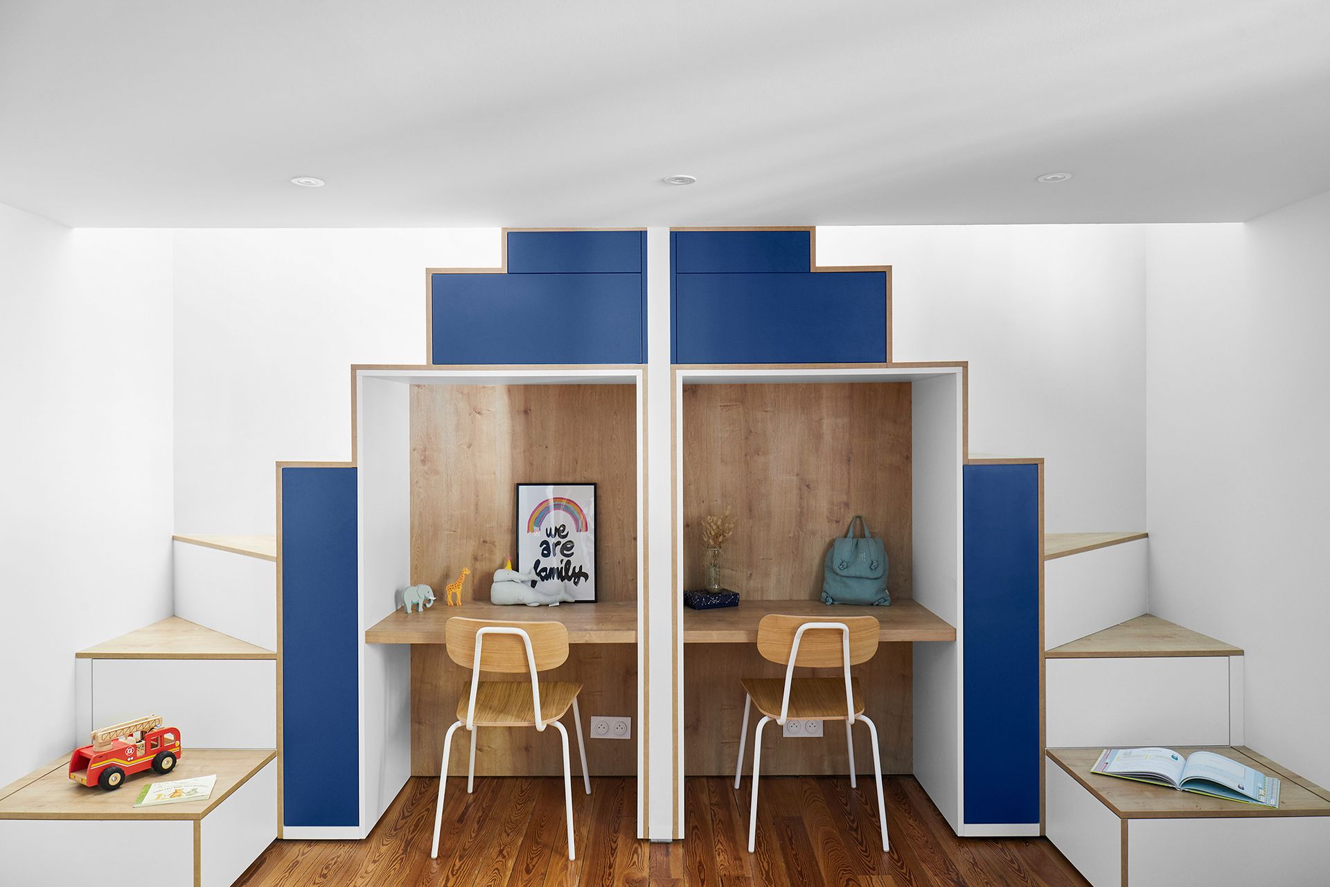 Chambre blanche moderne avec deux bureaux jumeaux, touches de bleu, chaises et lits avec étagères latérales intégrées