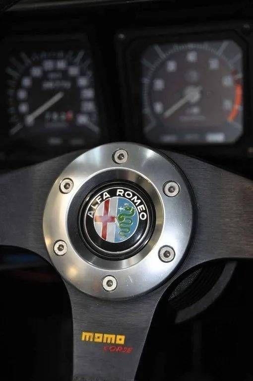 Volant Alfa Romeo avec logo Momo, centré devant les instruments du tableau de bord.
