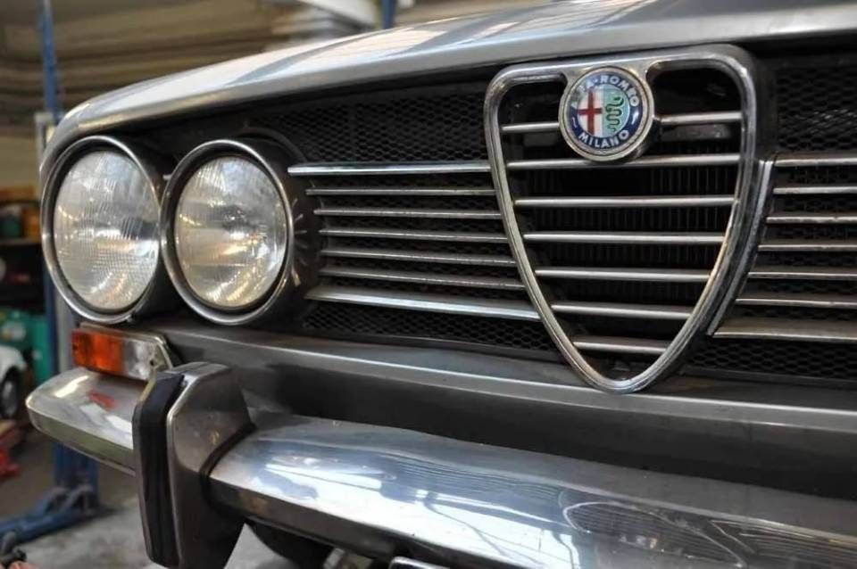 Gros plan sur la calandre d'une Alfa Romeo classique avec phares ronds et pare-chocs chromé