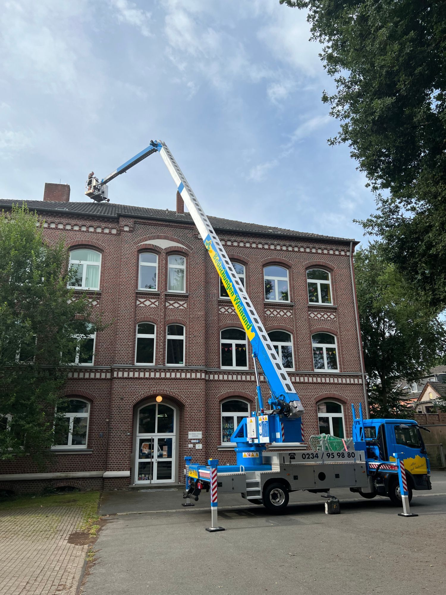 Autokran vor Dach einer Schule
