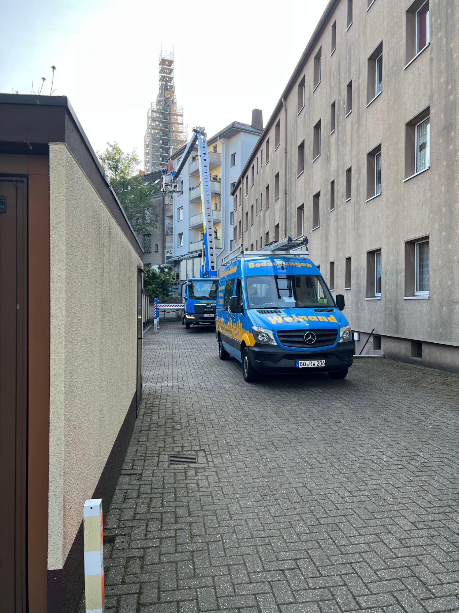 Firmenwagen und Hubwagen in einer schmalen Gasse einer Innenstadt