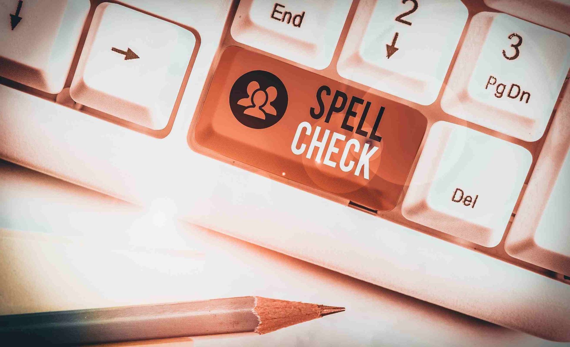 Un teclado con un botón de corrección ortográfica al lado de un lápiz.